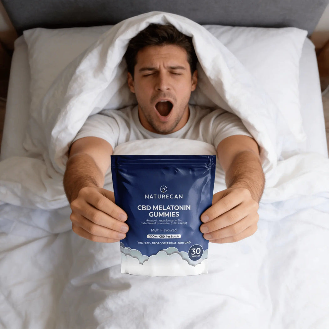 Man in bed holding a package of Naturecan CBD Melatonin Gummies