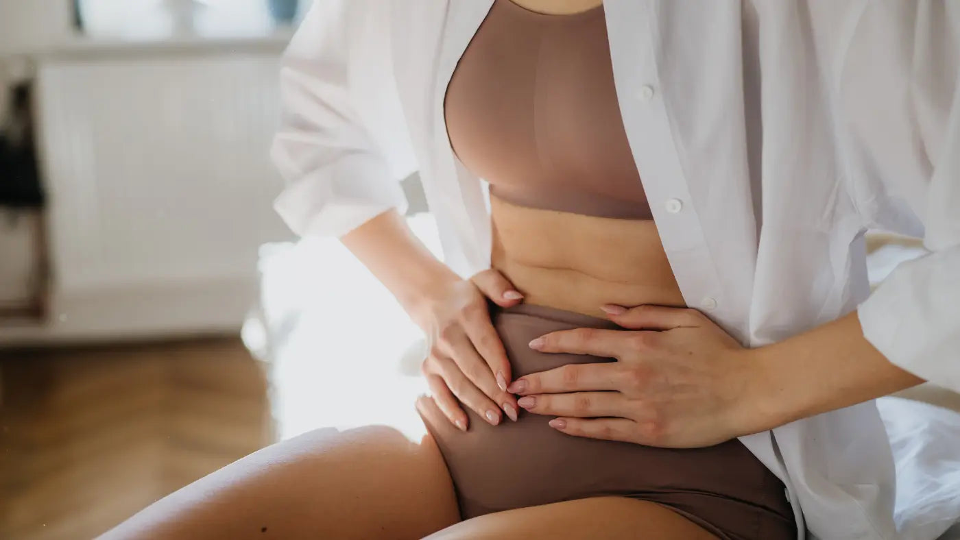 Woman with hands on stomach holding bloated stomach
