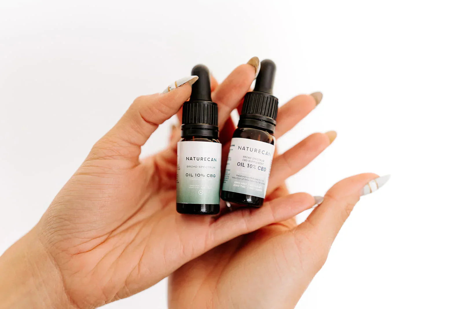 w bottles of CBD Oils in Hands