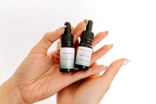 w bottles of CBD Oils in Hands