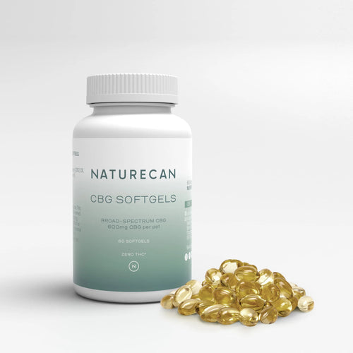 A bottle labeled "Naturecan CBG Softgels" stands beside a pile of golden capsules.