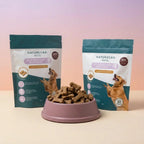 Two packages of Naturecan Pets dog treats with a bowl of treats in front on a gradient background.