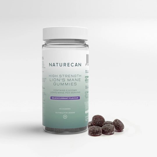 A jar of high strength Lion’s Mane Gummies with a white lid and blackcurrant flavor label, next to scattered gummies.