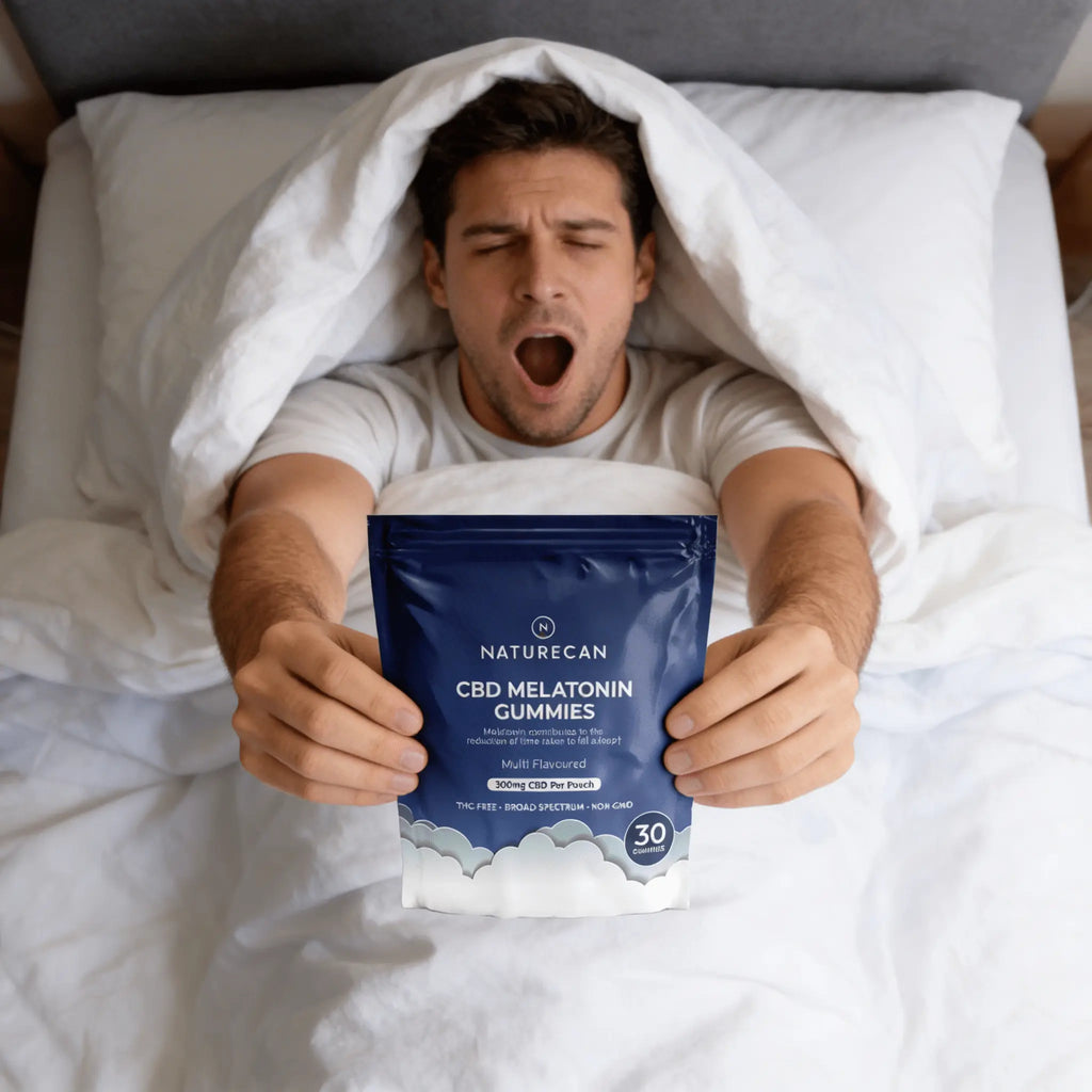 Man in bed holding a package of Naturecan CBD Melatonin Gummies