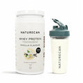Whey Protein Powder in a vanilla flavour container next to a shaker filled with a creamy vanilla drink.