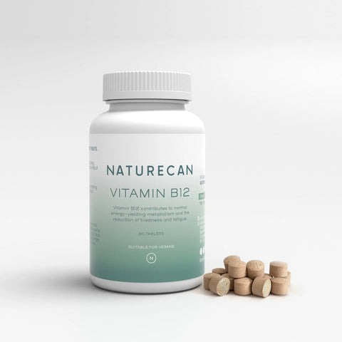 Bottle of Vitamin B12 from Naturecan with tablets scattered beside it on a white background.
