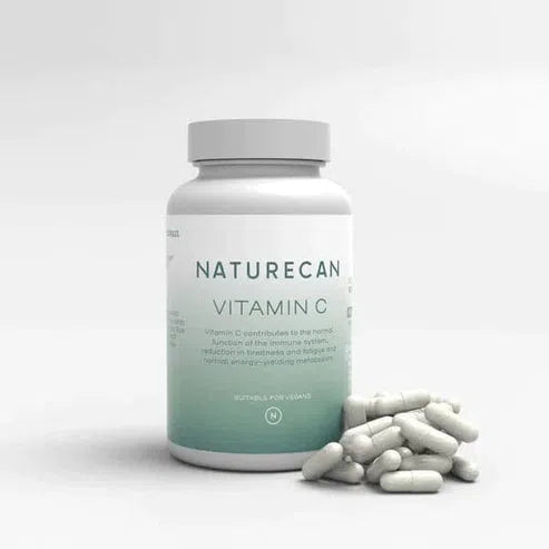 A bottle of Naturecan Vitamin C Capsules with some capsules scattered in front.
